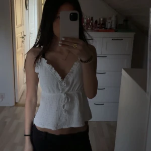 Volangtopp💕 - Supersöt vit topp med smala axelband, v-ringning och volangkant. Perfekt för sommarn!💕 Det är i storlek xs o är helt oanvänd 💓 Hör av er om ni har nå frågor 🥰