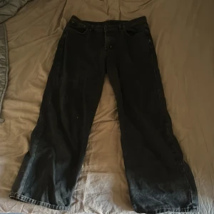 Svarta jeans med röd broderad design - Unika svarta jeans med bred passform och stor broderad tribal-inspirerad design i rött och vitt över bakfickorna.