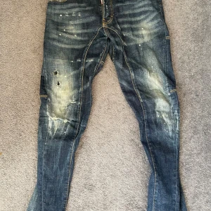 Dsquared2 jeans blå - Snygga blå Dsquared2 Caten-Twin jeans med slitningar, hål och lite färgstänk.