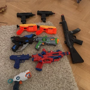Leksakspistoler och gevär, 6-pack - Paket med 8 olika leksakspistoler och ett gevär i plast. Flera färger och modeller, vissa med futuristisk design. Synligt använda men i gott skick, inga större skador. Perfekt för lek och rollspel.
