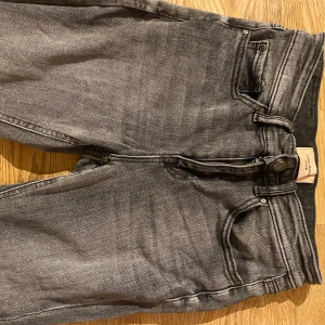 Grå bootcut jeans från Vero Moda  - Snygga grå jeans från Vero Moda  med bootcut-ben och klassisk femficksdesign. Finns slitage längst ner vid fotleden på jeansen pågrund av att dom varit för långa.