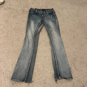 Blå bootcut jeans med coola fickor - Supersnygga lågmidjade blå bootcut jeans med coola fickor. Står inte storlek men skulle säga att de är 36. Liten slitning längst ner på jeansens baksida. Innerbenslängd: 84 cm, midjemått rakt över: 38 cm