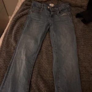 Blå jeans från Gina Tricot, stl 152 - Snygga blå jeans från Gina Tricot i klassisk femficksmodell. Jeansen har raka ben, normal passform och detaljer som knappar och läderpatch bak. Perfekta för dig som gillar en enkel och tidlös stil.