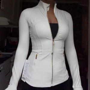 Lululemon Gold Zipper Ivory - Oanvänd sällsynt Ivory/Gold zipper lululemon define jacket, ny med prislapp säljs då storleken var fel. Storlek 4, svårt att hitta denna färg!