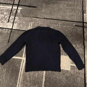 Mörkblå stickad tröja Massimo Dutti - Mörkblå stickad tröja från Massimo Dutti i en lyxig mix av ull och kashmir. Tröjan har rund halsringning, ribbade muddar och lång ärm. Enkel och stilren modell som är perfekt för kyligare dagar.