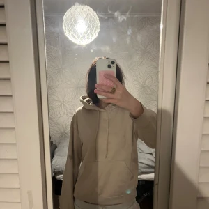 Beige hoodie med huva och ficka - Säljer en stilren beige hoodie med huva. Tröjan har en stor magficka och är i mjukt bomullsmaterial. Perfekt för chill dagar och enkel att matcha med andra plagg.