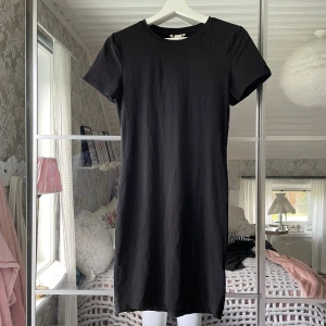 Svart t-shirtklänning  - Enkel svart t-shirtklänning i bomull med rund hals och korta ärmar. Modellen är tight och kort.