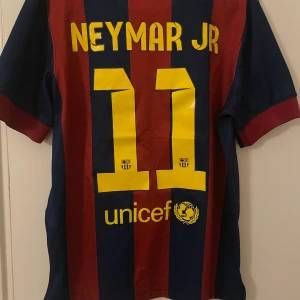  Neymar Jr Barcelona tröja - Säljer en officiell FC Barcelona Neymar Jr matchtröja från Nike i storlek M. Tröjan är blå och röd med gula detaljer, har klassiska vertikala ränder, klubbmärke, Qatar Airways-tryck och nummer 11 på ryggen. Tillverkad i lätt Dri-Fit material för bästa komfort.