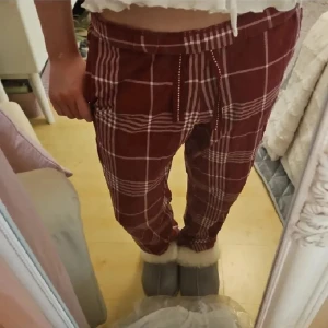 Röd-rutiga pyjamas byxor från Kappahl XS - Snygga röd-rutiga byxor från Kappahl i storlek XS. Byxorna har vitt rutmönster, elastisk midja med snörning och är gjorda i mjuk bomull. Byxorna är i storleken XS men passar mig som är 152 cm, så passformen är något kortare. Använt endast ett fåtal gånger, men i mycket bra skick. Nypris runt 200 kr. Populära! Ser ut som nya fast använda.
