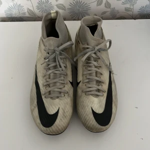 Nike Mercurial fotbollsskor gula/svarta - Säljer ett par Nike Mercurial fotbollsskor i vitt och svart med högt skaft och snörning. Skorna har en lätt och smidig syntetöverdel, klassisk Nike Swoosh och textdetaljer på sidan. Perfekta för dig som vill ha snabbhet och kontroll på planen.pris kan diskuteras och att den är smutsig men om du tvättar den så blir den riktig nice 