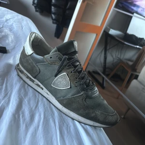 Philippe Model sneakers i grå mocka - Snygga sneakers från Philippe Model i grå och mörkgrön mocka och textil med vita detaljer. Skorna har snörning, rund tå och en unik mönstrad sula. Perfekta för dig som gillar stilrena men ändå unika sneakers. SKICKET ÄR HELT OKEJ SKULLE SÄGA MER EN OKEJ! 