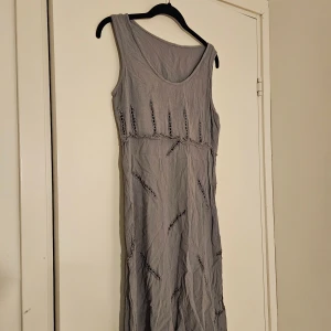 Klänning från Mexiko - Säljer en ljusgrå långklänning med broderade och utskurna detaljer över hela klänningen. Ärmlös modell med rund halsringning. Köpt i Mexiko. Tunt och skönt material. 