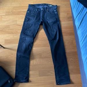 Replay Grover svarta jeans, stl 29 - Säljer ett par svarta Replay Grover jeans i storlek 29. Jeansen har klassisk femficksdesign, raka ben och snygg passform. Materialet är mjukt och stretchigt jeans, perfekt för dig som gillar stilrena och bekväma byxor.