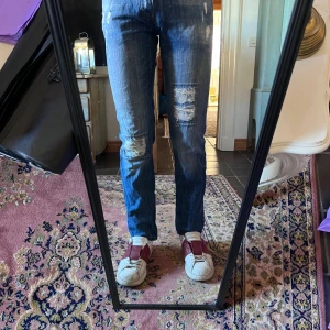 Blå slim jeans med slitningar Adrian Hammond size 29 - Säljer ett par blå jeans med slitningar och trasiga detaljer på knäna. Jeansen har raka ben och klassisk femficksmodell. De är i normal passform och har en snygg tvättad look som ger en cool vibe. Perfekta för dig som gillar en avslappnad och trendig stil. Modellen är 178cm 70kg midja 35cm längd 100cm (11)