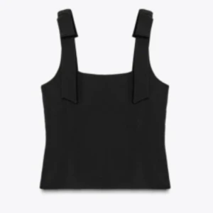 Svart linnetopp med breda axelband - Säljer en svart linnetopp med breda axelband och rak halsringning. Toppen har en figurnära passform och är ärmlös, perfekt att styla med jeans eller kjol. Materialet känns slätt och något stadigt, vilket ger en snygg siluett. Funkar som både finklätt och till basic outfits. Endast använd fåtal gånger