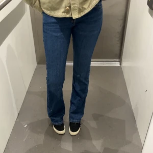 Blå Mira jeans bootcut W26 L32 - Säljer ett par klassiska blå jeans från Mira i modellen bootcut. Jeansen har låg midja, raka ben med lätt utsvängning och femficksdesign. Tillverkade i jeansmaterial med snygg mörkblå tvätt och kontrastsömmar. Perfekta för en chill och stilren look. Använd sfärisk gånger pg lite för korta