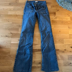 Blå bootcut jeans med fickor - Snygga blå jeans med bootcut-modell och markerade sömmar längs benen. Nästan aldrig använda och därav inga defekter. De är i storlek 32 men lite små i storleken, jag har sytt upp de så de passar någon som är cirka 160cm🥰🥰