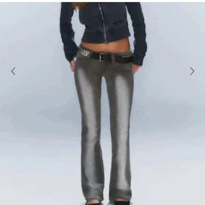 Grå bootcut jeans med låg midja - Säljer ett par grå jeans med snyggt slitna detaljer och bootcut-ben. Jeansen har låg midja och klassisk femficksdesign. Perfekta för dig som gillar en retro vibe och vill ha ett par jeans som sticker ut. Materialet är jeans och passformen är normal.