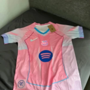Rosa Nike fotbollströja FC Barcelona S - Säljer en riktigt snygg FC Barcelona fotbollströja från Nike i rosa och ljusblå toner. Tröjan har korta ärmar, Dri-FIT-material och coola detaljer som klubbmärke, Nike-logga och Spotify-logga på bröstet. Perfekt för dig som vill sticka ut på planen.