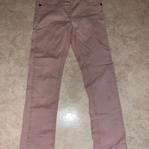 Rosa byxor från Mix, stl 128 - Säljer ett par ljusrosa byxor (mer rosa i verkligheten) från Mix i storlek 128. Byxorna har raka ben, klassiska fickor fram och bak samt resår i midjan. Dr passar perfekt för en avslappnad stil. Enkel liten fläck som jag ej provat få bort.