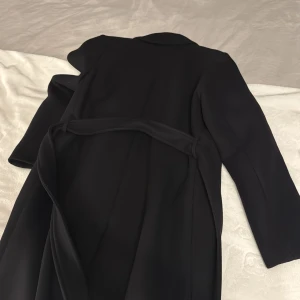 Lång Svart kappa från Filippa K - Kappa från Filippa K i storlek 34. Sparsamt använd och i mycket bra skick!