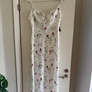 Vit blommig långklänning med snörning - Superfin långklänning i vitt med blommigt mönster. Helt ny, endast testad! 