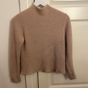 Ljusrosa stickad polotröja från Bik Bok - Supermysig ljusrosa stickad polotröja från Bik Bok i ribbat material. Tröjan har lång ärm och en hög hals som ger en snygg och enkel look.