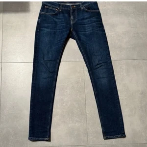 Nudie Jeans - Snygga mörkblå jeans från Nudie med klassiska fem fickor och kontrastsömmar. Modellen är Tight Long Terry och sitter slim fit. Storlek 32/34. Nypriset på dessa är 2000 och mitt pris 499✅