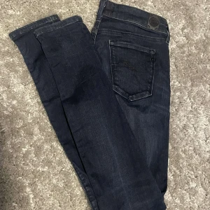 Mörkblå slimfit Replay jeans - Snygga mörkblå jeans från Replay med klassisk femficksdesign och diskreta detaljer. Jeansen har raka ben och slimfit passform. tillverkade i mjukt denimtyg med stretch för extra komfort. Perfekta för dig som gillar stilrena och tidlösa jeans.