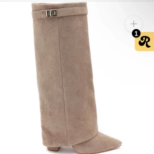 Beige foldoverboots med spetsig tå - Beiga foldover boots i mocka med spetsig tå. Stövlarna har dragkedja på insidan och dekorativt spänne.
