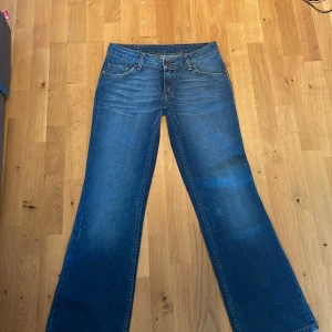 Blå bootcut jeans från Pepe Jeans - Snygga blå jeans från Pepe Jeans med snygg passform och klassiska detaljer. Jeansen har fem fickor, kontrastsömmar och Pepe Jeans-logga på bakfickan. Perfekta för dig som gillar en lite vidare siluett nertill och klassisk denimstil. ljusare slitage som ska se ut så