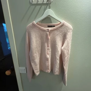 Ljusrosa kofta från lager 157, storlek S - Supermjuk och fluffig ljusrosa kofta från lager 157 med rund halsringning och knappar framtill. Långärmad modell i stickad kvalitet som är perfekt för lager-på-lager. Enkel och stilren design som passar till allt.