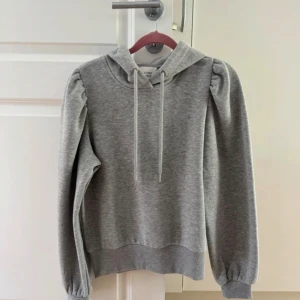 Grå hoodie med puffärmar - Grå hoodie med fina detaljer på axlarna från second Female, inga defekter! 