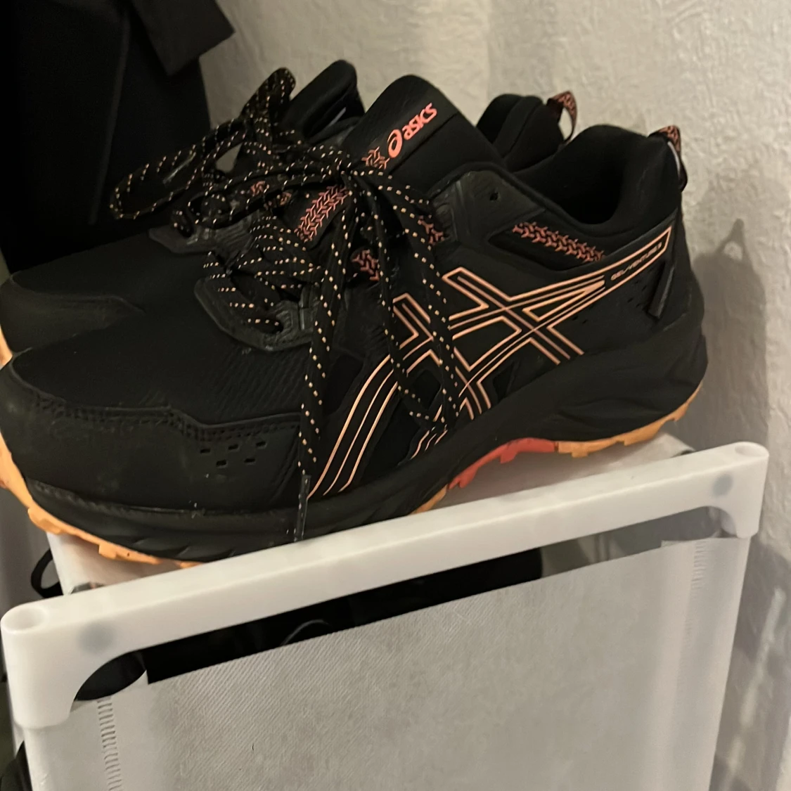 Svarta Asics sneakers med orange detaljer
