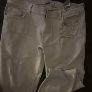Vita jeansbyxor  - Snygga vita  jeansbyxor med klassisk femficksdesign och bälteshällor. Byxorna har en rak passform och är tillverkade i bomullsmaterial som känns skönt mot huden. Perfekta för en stilren och avslappnad look.