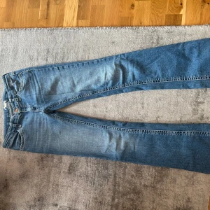 Blå jeans med kontrastsömmar - Snygga blå jeans från Gina tricot. Pyret med tydliga vita kontrastsömmar och klassiska fem fickor. Jeansen är low waist bootcut och har normal passform, samt detaljerade bakfickor med dekorativa knappar. Perfekta för en avslappnad stil.