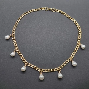 Guldfärgat halsband med droppformade pärlor - Stilrent halsband med kraftig guldfärgad kedja och sju droppformade vita pärlor som hänger längs hela kedjan. Perfekt för dig som vill ha en trendig accessoar med lyxig känsla och snygg kontrast mellan guld och pärlglans.