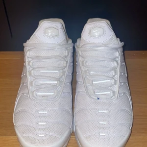 Nike tn  - Nike Air Max Plus Tn sneakers i helvitt med mesh- och syntetmaterial, ikoniska vågformade detaljer och synlig Air-dämpning i sulan. Skorna har snörning och Tn Air-logga bak. Perfekta för dig som gillar en clean och sportig look.