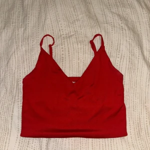 Röd linnetopp från Amisu - Snygg röd linnetopp från Amisu med smala axelband och v-ringning. Toppen är croppad och har en enkel, stilren design. Materialet känns mjukt och följsamt mot huden. 