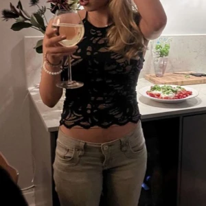 Stockholmstil Svart spetsig halter linnetopp - Säljer en svart topp i spets med ett snyggt mönster och halterneck. Toppen har en öppen rygg med knytband i halsen och fina spetsdetaljer längs kanterna. Perfekt för dig som vill ha en trendig och snygg look. Använd en gång och jag kan inte visa fler bilder eftersom den inte passar!