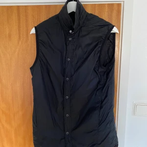 Svart dunväst från J.Lindeberg - Svart dunväst från J.Lindeberg med hög krage och knäppning framtill. Västen är i storlek S och passar för personer som är mellan 170-180. Priset kan diskuteras. Om du undrar något får du gärna höra av dig.