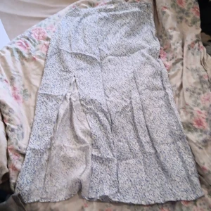 Blåvit blommig långkjol från H&M - Säljer en långkjol från H&M i storlek 38. Kjolen är vit med blått blommönster och har en luftig känsla, perfekt för varmare dagar. Tillverkad i ett mjukt bomullstyg som känns skönt mot huden. Kjolen har en rak passform och vackert fall.