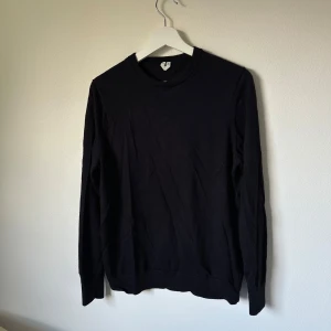 Mörkblå ulltröja från Arket, storlek M - En stilren mörkblå långärmad tröja från Arket i mjuk ull. Klassisk rund halsringning och ribbade muddar vid ärmslut och nederkant. Perfekt för lager-på-lager och enkel att matcha med allt i garderoben. 2I8