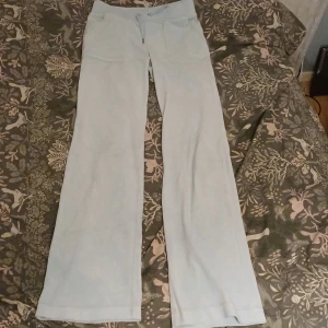 Ljusblå fleecebyxor med fickor - Mysiga ljusblå byxor i fleece med bred resår i midjan och stora fickor både fram och bak. Byxorna har raka ben och är perfekta för chill eller hemmadagar. Snygga detaljer med knappar på bakfickorna för extra stil. Finns två små fläckar på främre högre ben. Men syns knappt. (Se bild 3)