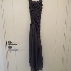 Mörkgrå långklänning från zara - Supersnygg mediumlång klänning i mörkgrått från zara, storlek S. Klänningen har smala axelband och coolt rynkade detaljer över hela överdelen som ger en unik look. Kjolen faller mjukt och har en flowy känsla. 