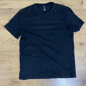 Svart slim fit t-shirt från H&M - En svart t-shirt från H&M i slim fit-modell. Klassisk rund halsringning och korta ärmar. Tillverkad i mjuk bomull som känns skön mot huden. Perfekt basic-plagg att ha i garderoben.