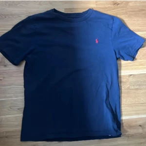 Marinblå t-shirt från Polo Ralph Lauren - Tjena! Säljer denna as snygga polo tshirten. Den är riktigt snygg och skön för att ha under hoodien eller jackan eller att ha på sig om det är varmt. Ny pris (600kr) den har ett litet litet hål som knappast märks. Har ni minsta lilla fråga så är det bara att skriva.!
