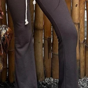 Bruna mjukisbyxor med snörning - Snygga bruna mjukisbyxor med bootcut och kontrastsömmar. Byxorna är lågmidjade och en vit dragsko i midjan för extra stilpoäng. 