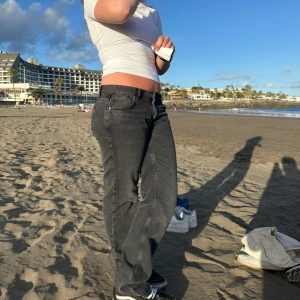 Svarta raka jeans - Säljer ett par svarta baggy low waist jeans med rak passform och klassisk femficksdesign. Jeansen har en låg midja och är tillverkade i ett mjukt denimtyg som ger en avslappnad look. Perfekta för dig som gillar en enkel och stilren stil.