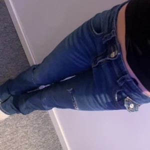 Gina Tricot jeans  - Säljer ett par blå jeans från Gina tricot med egen gjorda slitningar på låren och knäna.Dem är i bra skick men dem har ett litet slit på baksidan av jeansen. Säljer för 175kr😊